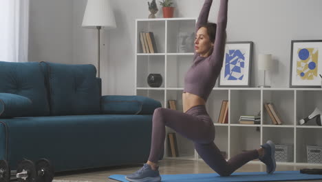 athletic-woman-is-doing-warrior-pose-at-yoga-training-at-home-stretching-hands-up-sporty-and-healthy-lifestyle-slender-sportswoman-in-room